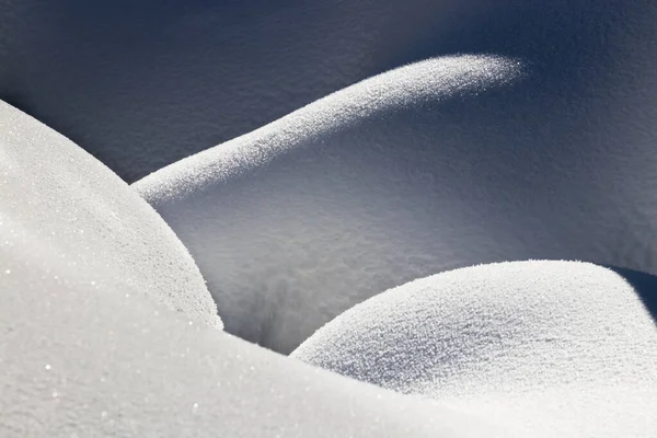 Bella trama linee lisce di cumuli di neve gioco di luce e ombra di un paesaggio invernale sullo sfondo — Foto Stock