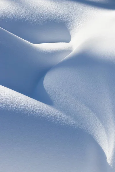Mooie gladde lijnen textuur van sneeuwverschuivingen spelen van licht en schaduw van een winterlandschap op de achtergrond Stockfoto