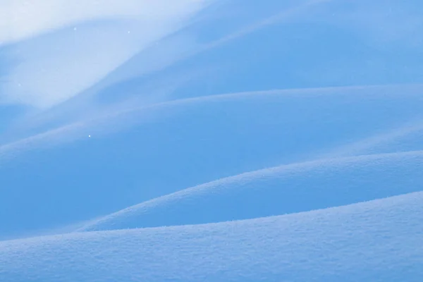 Bella trama linee lisce di cumuli di neve gioco di luce e ombra di un paesaggio invernale sullo sfondo — Foto Stock