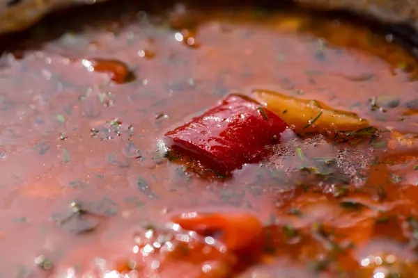 Hot beef hungarian goulash or bograch soup with paprika, small egg pasta, vegetables and spices in a pot on wooden table, classic recipe, view from above, close-up