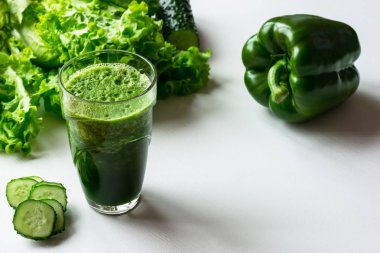 Bir bardak beyaz zemin üzerine yeşil sebze güler yüzlü. Kopya alanı.