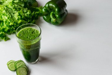 Bir bardak beyaz zemin üzerine yeşil sebze güler yüzlü. Kopya alanı.