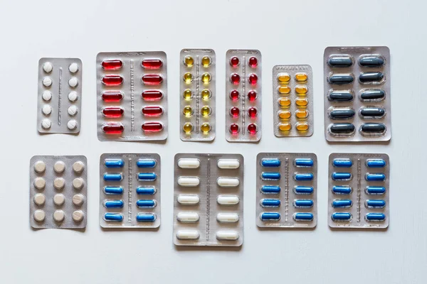 Set di blister di pillole colorate su uno sfondo bianco. Posa piatta . — Foto Stock