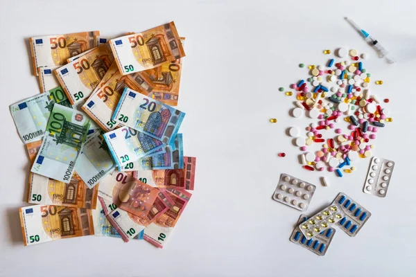 Деньги и таблетки. Таблетки разных цветов на белом фоне . — стоковое фото