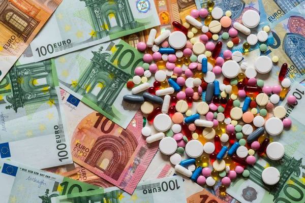 Красочные таблетки таблетки наркотики на фоне денег — стоковое фото