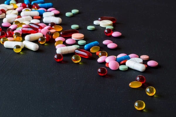 Farklı renkli ilaçlar. Hap ve kapsül siyah arka plan üzerine. Kopya alanı.