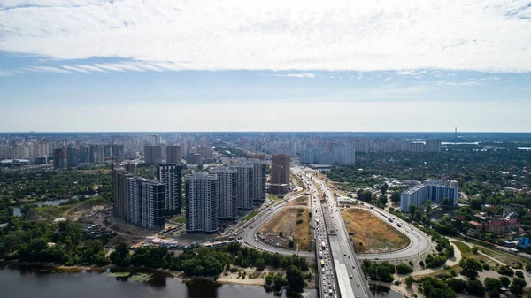 Puente Sur. Vista aérea de muchos edificios. El río Dniéper. Verano. El sol. Un día. Árboles verdes. Edificios altos. Camino. Autos. Infraestructura. Cielo. Las nubes. Kiev. . — Foto de Stock