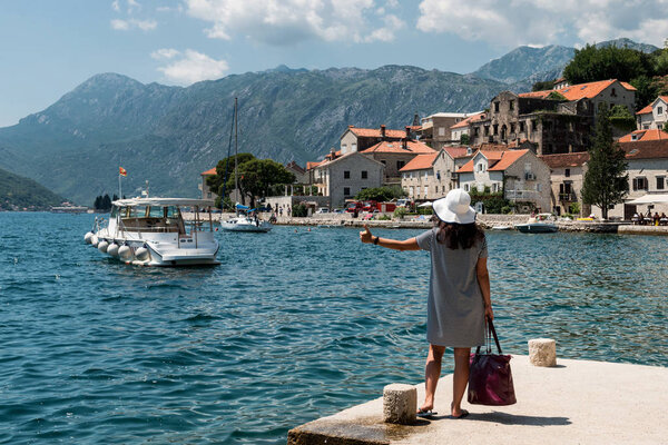 Woman hitchhiking on a pier. A girl is waiting for a boat on the pier