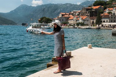 Bir iskelede otostop kadın. İskelede bir tekne için bekleyen bir kız
