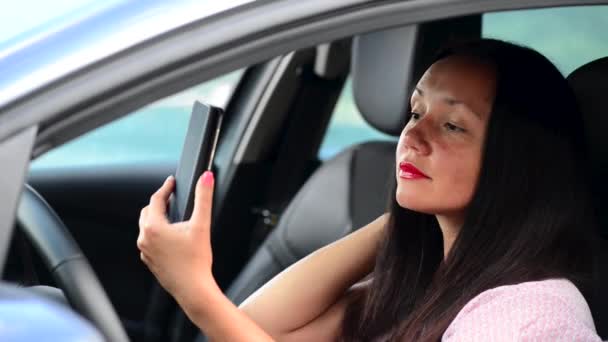 Vacker ung flicka gör selfie på smartphone och leende i bilen — Stockvideo