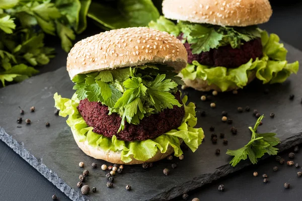 Two vegan burgers with beet cutlet on black background. Healthy fastfood. Vegan food
