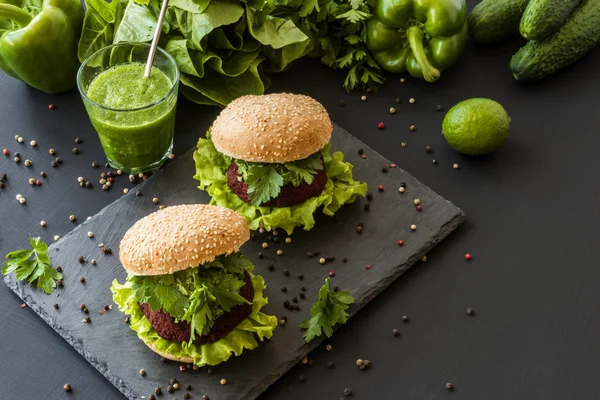 Vegan burgers with beet cutlet and green smoothies on black background. Healthy vegan food. Detox diet.