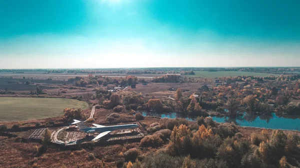 Letecký pohled na letadla v podzimním lese nedaleko jezera a krásná krajina. Krásná podzimní krajina s letadlem. — Stock fotografie