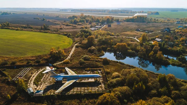 Letecký pohled na letadla v podzimním lese nedaleko jezera a krásná krajina. Krásná podzimní krajina s letadlem. — Stock fotografie