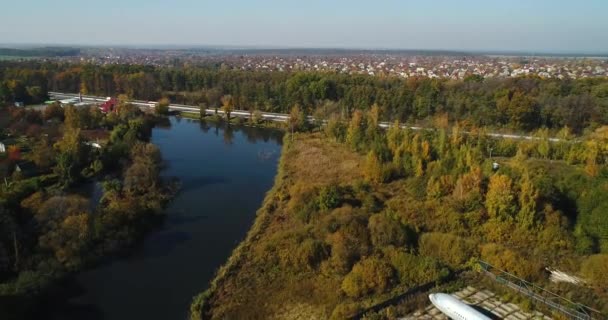 A légi felvétel a gépet az őszi erdő közelében a tó és a gyönyörű táj. Szép őszi táj, és egy olyan sík. — Stock videók