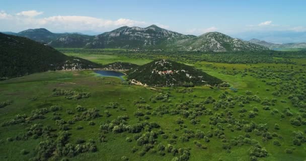 Letecký pohled na krajinu Skadarské jezero v pohoří a ostrov s klášterem na krásný slunečný den. Černá Hora. Území jezera Skadarské zarostlá rostlinami. — Stock video