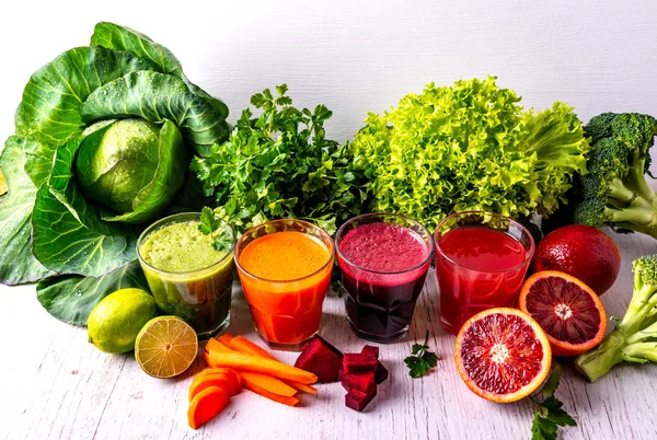 Différentes boissons végétaliennes saines avec des fruits et légumes sur le fond en bois blanc . — Photo