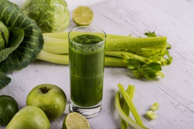 Ahşap masa üzerinde malzemelerle karışık yeşil smoothie. Dexox içecek