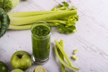 Ahşap masa üzerinde malzemelerle karışık yeşil smoothie. Dexox içecek