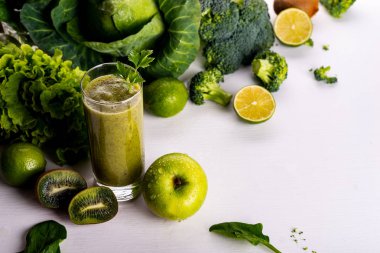Beyaz ahşap zemin üzerine yeşil smoothie kivi içki. Çiğ yiyecek ve içecek.