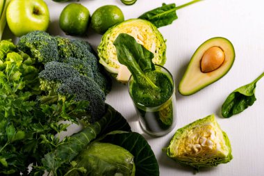 Beyaz ahşap arka planda avokado, kireç ve ıspanak ile Smoothie içecek. Çiğ yiyecek ve içecek. Düz yatma.