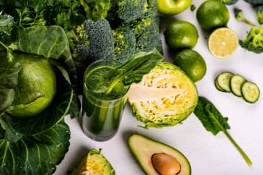 Beyaz ahşap arka planda avokado, kireç ve ıspanak ile Smoothie içecek. Çiğ yiyecek ve içecek. Düz yatma.