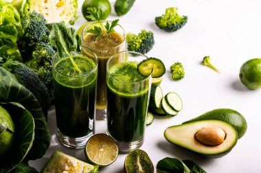 Beyaz ahşap arka planda farklı Sağlıklı Vegan ıspanak, kivi ve salatalık içecekler. Çiğ içecekler ve gıdalar. Düz yatma.