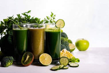 Beyaz ahşap arka planda farklı Sağlıklı Vegan ıspanak, kivi ve salatalık içecekler. Çiğ içecekler ve gıdalar.