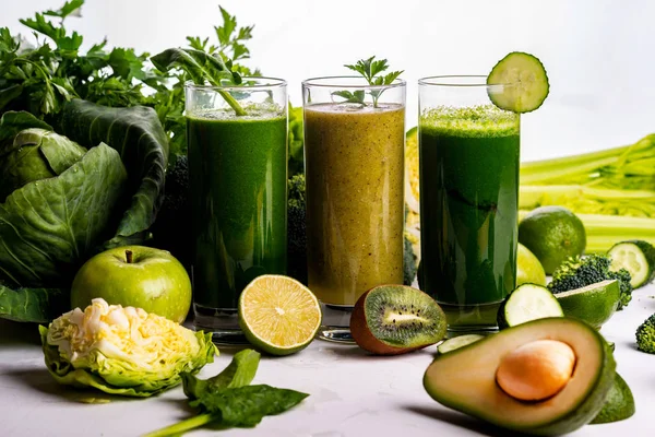 Verschillende gezonde veganistische spinazie, kiwi en komkommer dranken op de witte houten achtergrond. Rauwe dranken en voedingsmiddelen. — Stockfoto