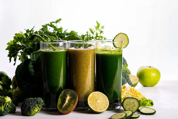 Různé zdravé špenát, kiwi a okurky na bílém dřevěném pozadí. Surové nápoje a potraviny. — Stock fotografie
