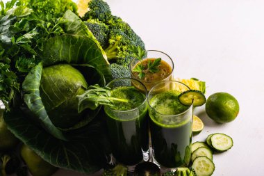 Beyaz ahşap arka planda ıspanak, kivi ve salatalık ile Vegan yiyecek ve içecekler. Çiğ içecekler ve gıdalar. Makro