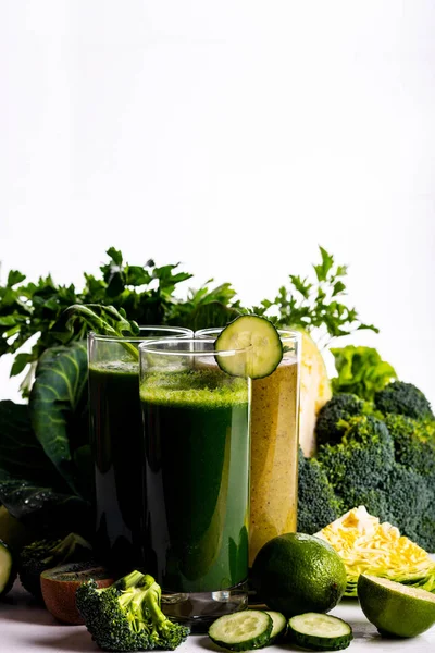 Χορτοφαγική τροφή και ποτά με σπανάκι, ακτινίδιο και αγγούρι στο λευκό ξύλινο φόντο. Ωμά ποτά και τροφές. — Φωτογραφία Αρχείου