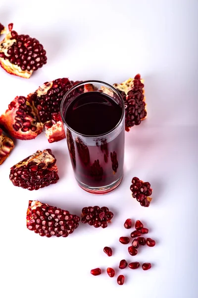 Glass of juice with a some pieces of pomegranate on a white background. — Stock Photo, Image