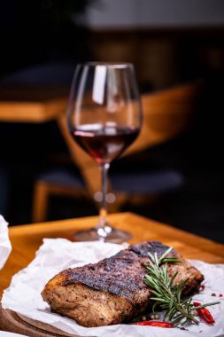 Striploin ızgara sığır eti biberiye, tuz ve biberiye ile ahşap tahta şarap cam ile servis.