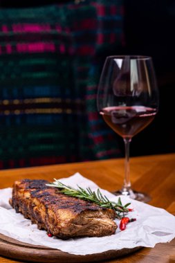 Striploin ızgara sığır eti biberiye, tuz ve biberiye ile ahşap tahta şarap cam ile servis.