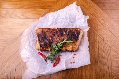 Kesme tahtası üzerinde otlar ile kavrulmuş domuz filetosu. Üstte görüntü.