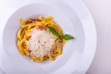 Klasik Carbonara makarna, pancetta ile spagetti, pastırma, yumurta, parmesan peyniri ve beyaz arka plan üzerinde yeşil arugula.