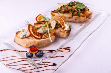 Beyaz arka planda peynir, bal, ceviz ve kuru portakal dilimleri ile meze bruschetta. Close.