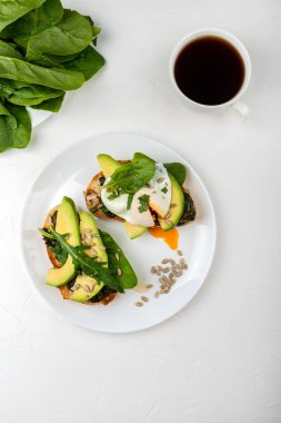 Kahvaltı. Ispanak, taze arugula ve tohum ve kahve bir fincan ile haşlanmış yumurta ve avokado ile Ekmek tost