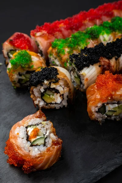 Somon ile Suşi rulo Philadelphia, füme eel, avokado, siyah arka plan üzerinde krem peynir. Suşi menüsü. Japon yemekleri.