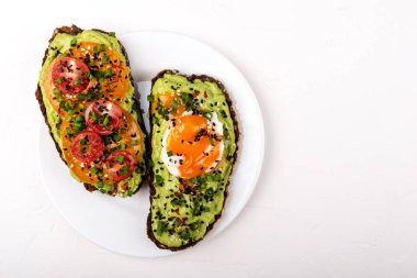 Avokado guacomole, yumurta ve domates, yeşil pırasa ve susam ile Sandviçler. Beyaz arka planda sağlıklı kahvaltı veya atıştırmalık. Kopyalama alanı.