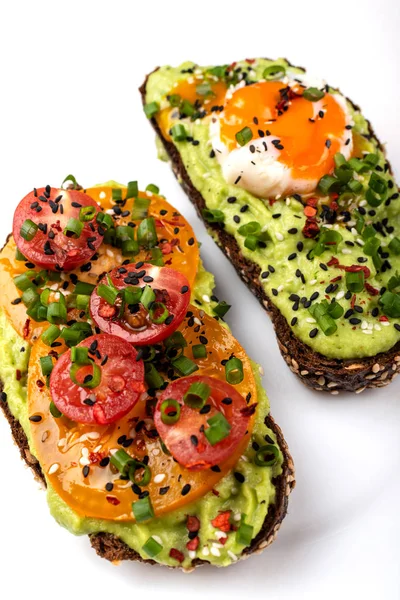 Avokado guacomole, yumurta ve domates, yeşil pırasa ve susam ile Sandviçler. Beyaz arka planda sağlıklı kahvaltı veya atıştırmalık.