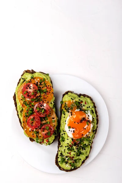 Avokado guacomole, yumurta ve domates, yeşil pırasa ve susam ile Sandviçler. Beyaz arka planda sağlıklı kahvaltı veya atıştırmalık. Kopyalama alanı.