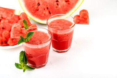 Karpuz smoothie nane ile taze meyve suyu, kalpler ve karpuz dilimleri şeklinde karpuz parçaları. Beyaz arka planda gözlüksağlıklı içecekler.