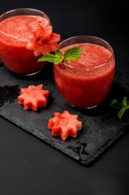 Karpuz smoothie siyah bir arka plan üzerinde yıldız şeklinde nane ve adet taze meyve suyu. Yaz sağlıklı içecekler.
