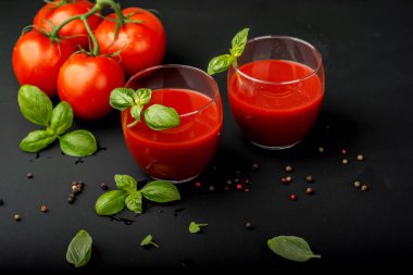 Siyah arka planda fesleğen ve kiraz domatesli taze domates suyu. Yakın plan..