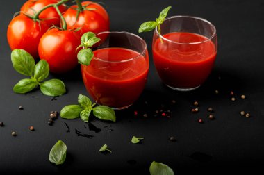 Siyah arka planda fesleğen ve kiraz domatesli taze domates suyu.