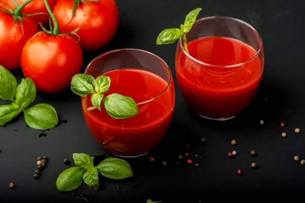 Tomatensaft mit Basilikum und Kirschtomaten auf schwarzem Hintergrund. Nahaufnahme. — Stockfoto