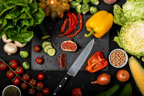 Legumes frescos diferentes em um fundo preto. Comida vegetariana saudável. Vista superior . — Fotografia de Stock