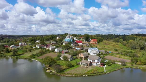 Légi kilátás gyönyörű Village Tájkép egy dombon, közel a tóhoz. A kamera előtérbe helyezése a témában. — Stock videók